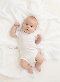 a baby laying on top of a white blanket