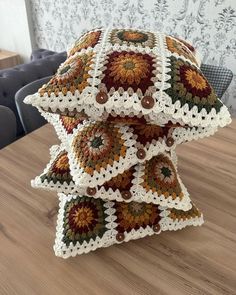 a stack of crocheted pillows sitting on top of a wooden table