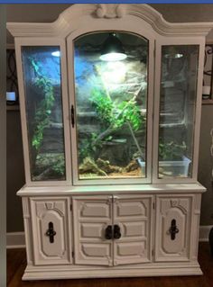 an aquarium is in the corner of a white hutch with drawers and cupboards