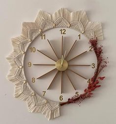 a white clock with gold hands and numbers on the face is decorated with red flowers