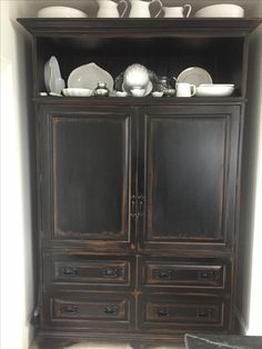 an old china cabinet with dishes on top