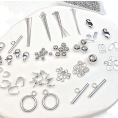 there are many different metal items on the white table together, including scissors and pins