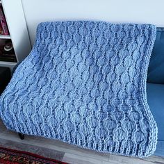 a blue blanket sitting on top of a couch next to a book shelf filled with books