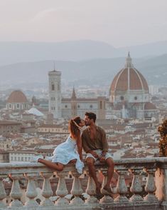 a man and woman sitting on top of a building next to each other