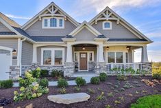 a house that is in the middle of some plants and flowers on the front lawn