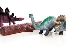 three toy dinosaurs are standing next to each other