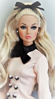 a doll with blonde hair wearing a white dress and black bow on it's head