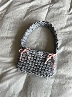 a crocheted purse sitting on top of a white bed next to a pillow