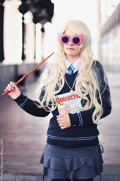 a woman with long blonde hair and glasses holding an umbrella in front of her face