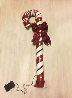 a red and white candy cane with a bow on it next to a charger