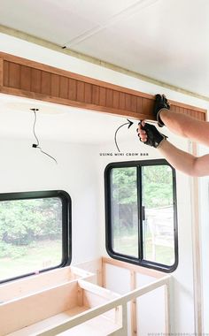 a man is working on the inside of a mobile home with windows and wood trimming