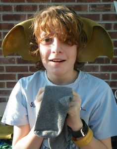 a young boy wearing an elephant hat on top of his head and holding a towel