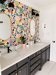 a bathroom with two sinks, mirrors and wallpaper on the walls in different colors