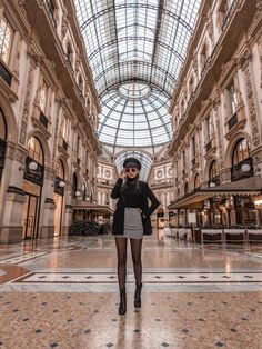 a woman is standing in the middle of an indoor mall