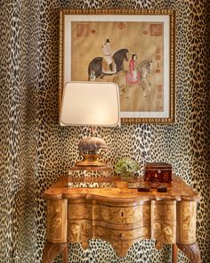 a painting on the wall above a leopard print dresser with a lamp and other items