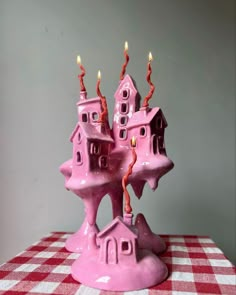 a pink castle candle holder sitting on top of a checkered tablecloth covered table