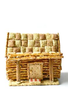 a miniature house made out of crackers on a white surface with the door open