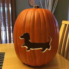 a pumpkin with a dachshund cut out on it sitting on a table