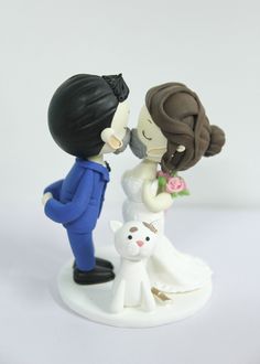 a figurine of a bride and groom kissing with a cat on their wedding day