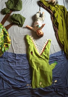 a baby laying on top of a bed next to clothes