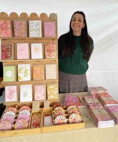 a woman standing in front of a table full of greeting cards and boxes with flowers on them