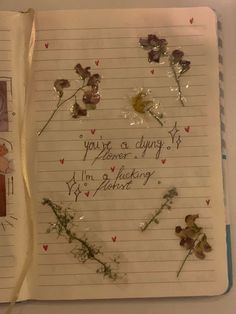 an open notebook with writing on it and flowers attached to the pages that have been left over