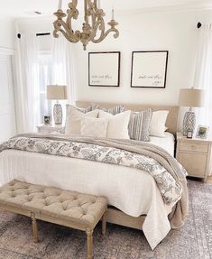 a bedroom with a bed, chandelier and two pictures hanging on the wall