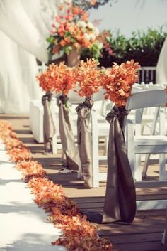 two vases filled with flowers sitting on top of a wooden floor next to white chairs