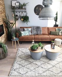 a living room filled with lots of furniture and plants on top of a white rug