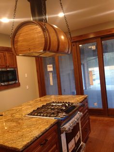 a kitchen with an oven, stove and wine barrel hanging from the ceiling above it