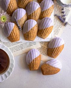 lavender cupcakes with white frosting on a plate next to a cup of coffee