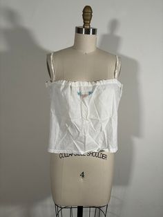 Antique Edwardian/ 1920s cotton camisole corset cover. Has wonderful embroidered on the front and an interior drawstring around the neckline.  The piece is in good shape. There are very small orange/brown stains throughout the front and back- see images.  Measurements- Bust- Max 40" Length- 11.5" Cotton Camisole With Floral Embroidery, Cotton Floral Embroidered Camisole, Floral Embroidery Cotton Camisole, Cotton Sleeveless Camisole With Floral Embroidery, Spring Cotton Camisole With Floral Embroidery, Spring Floral Embroidered Cotton Camisole, Spring Floral Embroidery Cotton Camisole, Sleeveless Cotton Crop Top With Tie Straps, White Floral Embroidery Camisole Tank Top