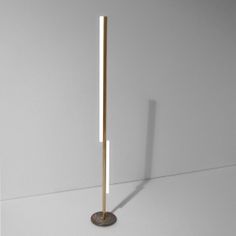 a metal pole with a wooden base on a white surface in front of a wall