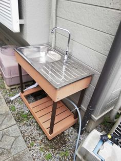 a sink sitting on top of a wooden stand next to a building with a hose