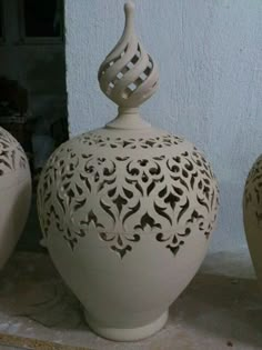 three white vases sitting next to each other on top of a stone countertop