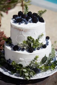 a three tiered cake with berries and greenery on top