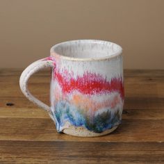 a colorful coffee cup sitting on top of a wooden table