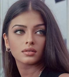 a woman with long brown hair and large earrings on her head is looking at the camera