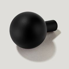 a black object sitting on top of a white floor next to a shadowless wall