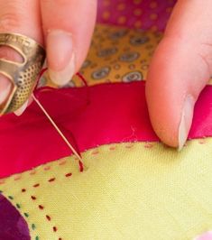 a woman is stitching something on a piece of fabric with a sewing needle in her hand