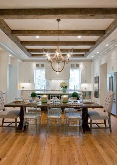 a large dining room table and chairs in front of a chandelier hanging from the ceiling