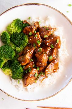 a white plate topped with meat and broccoli covered in gravy on top of rice