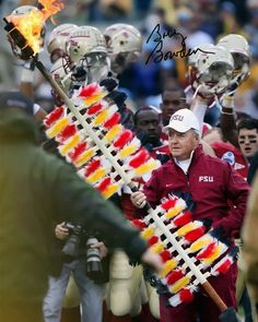 a football player holding a fire stick in front of other players on the sidelines