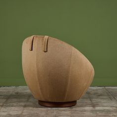 a brown chair sitting on top of a tiled floor next to a green wall with a wooden base