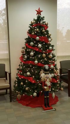 a decorated christmas tree in an office cubicle with red ribbon and decorations on it