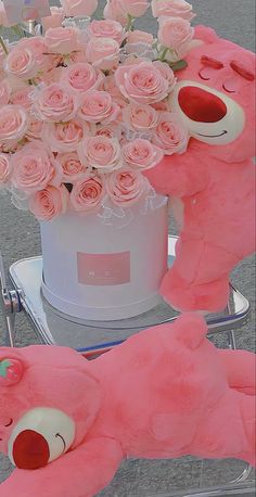 a pink teddy bear sitting next to a large bouquet of roses