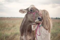 a woman is hugging a cow in a field