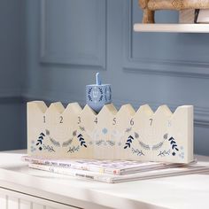 a wooden clock sitting on top of a white table next to a stack of books