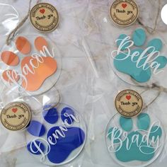 three different colored dog tags with the words, name and paw prints on them in plastic bags