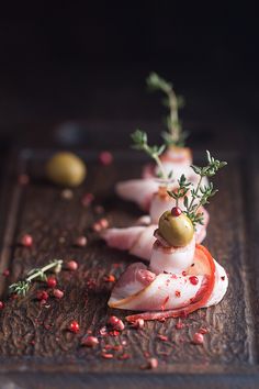 small appetizers are arranged on a wooden board with garnishes and olives